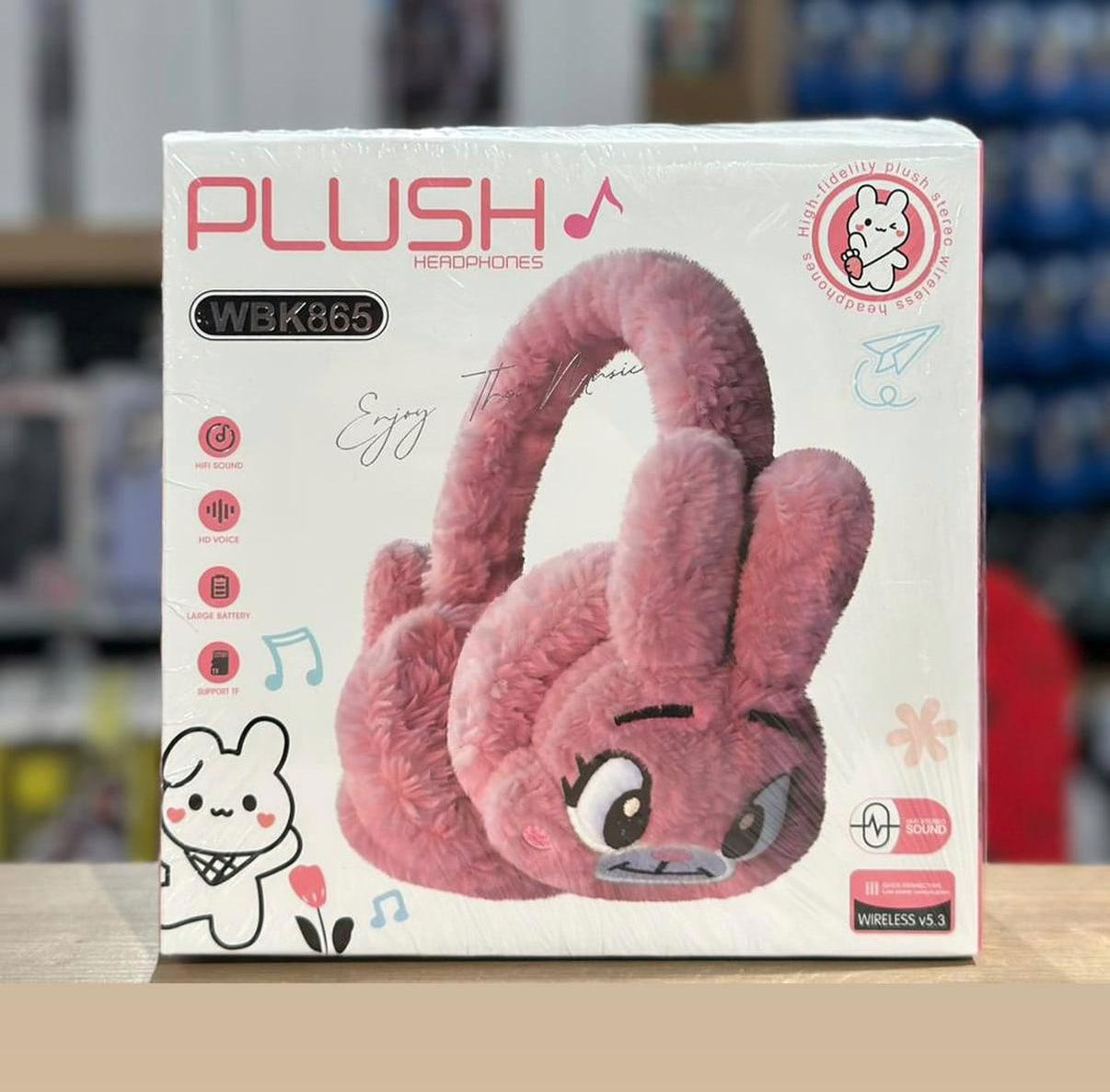Pink plush headphones on a box with branding and product details.