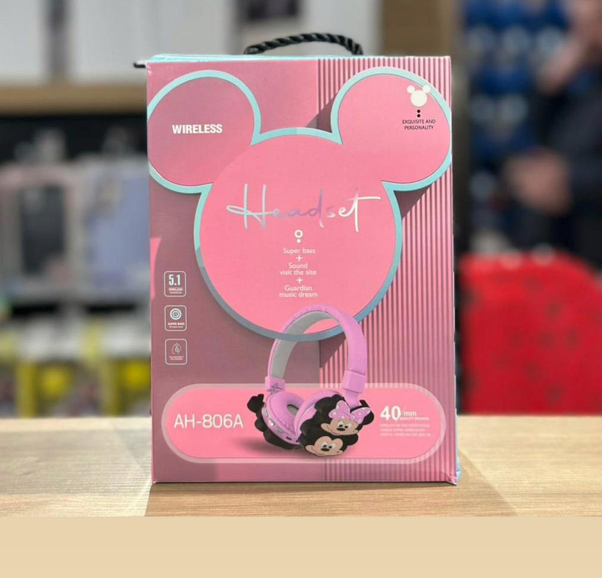 Pink headset packaging with Minnie Mouse design on a wooden surface